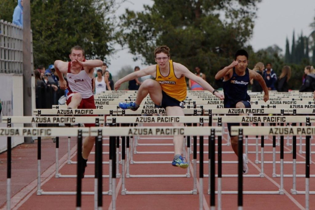 Three men jumping over hurdles